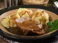 Karkówka w sosie własnym z purée ziemniaczanym, udekorowana natką pietruszki. Pyszny sos do karkówki idealnie komponuje się z ziemniakami.