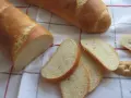 Chrupiąca bułka wrocławska, pokrojona w kromki, leży obok całej bagietki na lnianym obrusie.