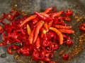 Ostry jak diabli! Całe mnóstwo czerwonych papryczek chili, niektóre pokrojone w plasterki, leżą w kamiennym moździerzu. To zapowiada najostrzejszą paprykę!