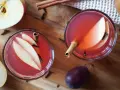 Dwa kieliszki aromatycznego kompotu z jabłek i gruszek, ozdobione laskami cynamonu i goździkami.