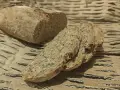 Chleb orkiszowy przepis: świeżo upieczony bochenek i kromki z ziarnami na brązowym tle.