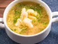 Aromaticzna zupa zacierkowa z koperkiem, podana w białej miseczce na granatowym obrusie.