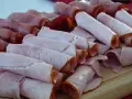 Roladki z szynki i wędliny, pięknie ułożone na desce. Czy to kindziuk? Nie, to pyszne mięsne przekąski!