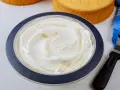 Puszysta bita śmietana z mascarpone w misce, gotowa do dekorowania biszkoptów.