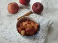 Miseczka z gotowanymi jabłkami do szarlotki, obok laska cynamonu i świeże jabłka.