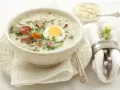 Aromaticzny żurek z białą kiełbasą i jajkiem, podany w misce, z dodatkiem ziół i marchewki. Idealny prosty przepis na żurek.