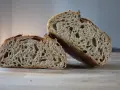 Chleb pszenno żytni na zakwasie, przekrojony na pół, ukazuje puszysty miąższ z licznymi dziurami i chrupiącą skórkę.