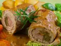 Dwa soczyste zrazy wieprzowe w sosie, podane z pieczonymi ziemniakami i warzywami.
