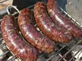Cztery soczyste kaszanki na grilla, rumieniące się nad żarem. Idealne na letnie spotkanie.