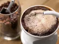 Parzenie aromatycznej kawy sypanej metodą przelewową. W tle słoik z ziarnami kawy.