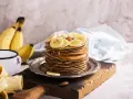 Stos naleśników z plasterkami banana i orzechami. Idealny pomysł, co zrobić z bananów na pyszne śniadanie.