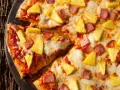 Pyszna pizza z ananasem i szynką, z ciągnącym się serem i chrupiącym ciastem. Idealna na szybki obiad.