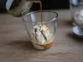 Gorące espresso zalewa gałkę lodów waniliowych, tworząc pyszne affogato.