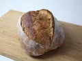 Chleb wiejski z chrupiącą skórką i puszystym wnętrzem, gotowy do pokrojenia na desce.