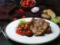 Soczysty udziec wołowy z salsą pomidorową i ziemniakami. Danie wygląda apetycznie.