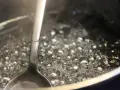Gotowy syrop cukrowy w trakcie gotowania. Bąbelki unoszą się na powierzchni, a łyżka sprawdza konsystencję. Idealny przepis na domowy syrop.