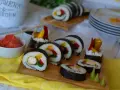 Pyszne sushi z kurczakiem, papryką i mango. Podane na desce z dodatkami: marynowanym imbirem i wasabi.