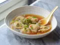 Aksamitna zupa wonton z kawałkami chili i szczypiorku, gotowa do nabrania łyżką.