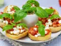 Bruschetta z pomidorami i mozzarellą, świeża bazylia i chrupiące pieczywo. Idealny przepis na letnią przekąskę.