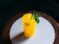 Orzeźwiający koktajl z mango, z lodem i listkami mięty, podany w szklance ze słomką.