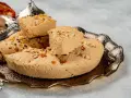 Chałwa turecka z migdałami i pistacjami na ozdobnej tacy. Słodki przysmak w kawałkach, zachęcający do degustacji.