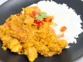 Kurczak w sosie curry z ryżem, posypany papryką i kolendrą. Prosty przepis na pyszny obiad.