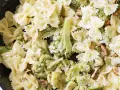 Pyszny makaron farfalle z brokułami w kremowym sosie śmietanowym, posypany orzechami włoskimi.