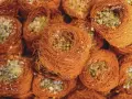 Słodkie gniazdka z cienkiego ciasta kataifi, wypełnione zielonymi pistacjami i posypane cukrem.