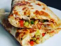 Złocista tortilla z jajkiem, serem i szynką, wypełniona warzywami, usmażona na patelni. Pyszne danie na szybki posiłek.