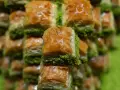 Słodka baklava, co to za przysmak? Warstwy ciasta filo, orzechów i syropu, posypane zielonymi pistacjami.