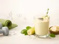 Zdrowy koktajl bananowy z nasionami chia, idealny po treningu. Obok leżą hantle i mata do ćwiczeń.