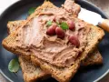 Pyszna pasta z czerwonej fasoli na chrupiących tostach pełnoziarnistych, udekorowana fasolkami i listkami ziół.