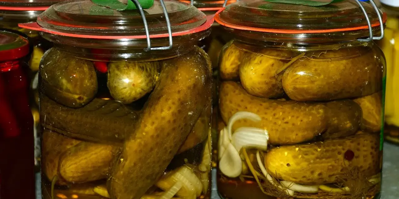 Słoiki pełne ogórków po kaszubsku, z dodatkiem cebuli i przypraw. Domowe przetwory gotowe na zimę.