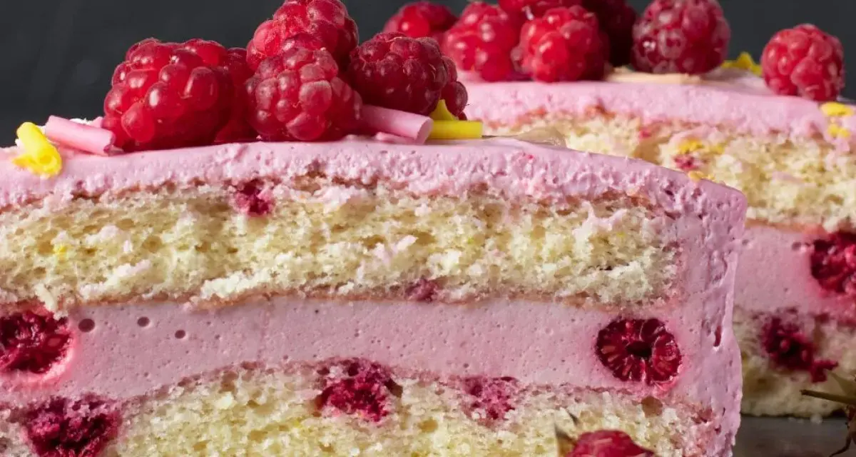 Pyszny tort z warstwami biszkoptu, przełożony kremem malinowym z mascarpone i świeżymi malinami.