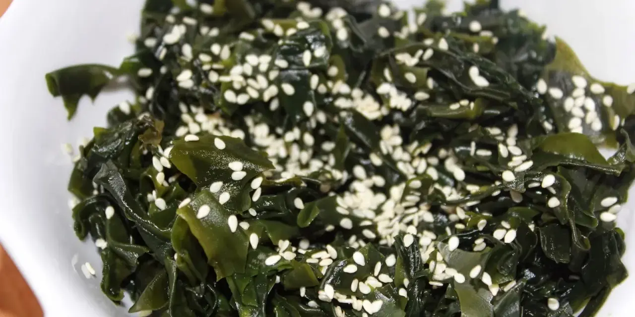 Sałatka z wodorostów wakame, posypana sezamem. To pyszne i zdrowe danie, które warto spróbować, jeśli zastanawiasz się, wakame co to.