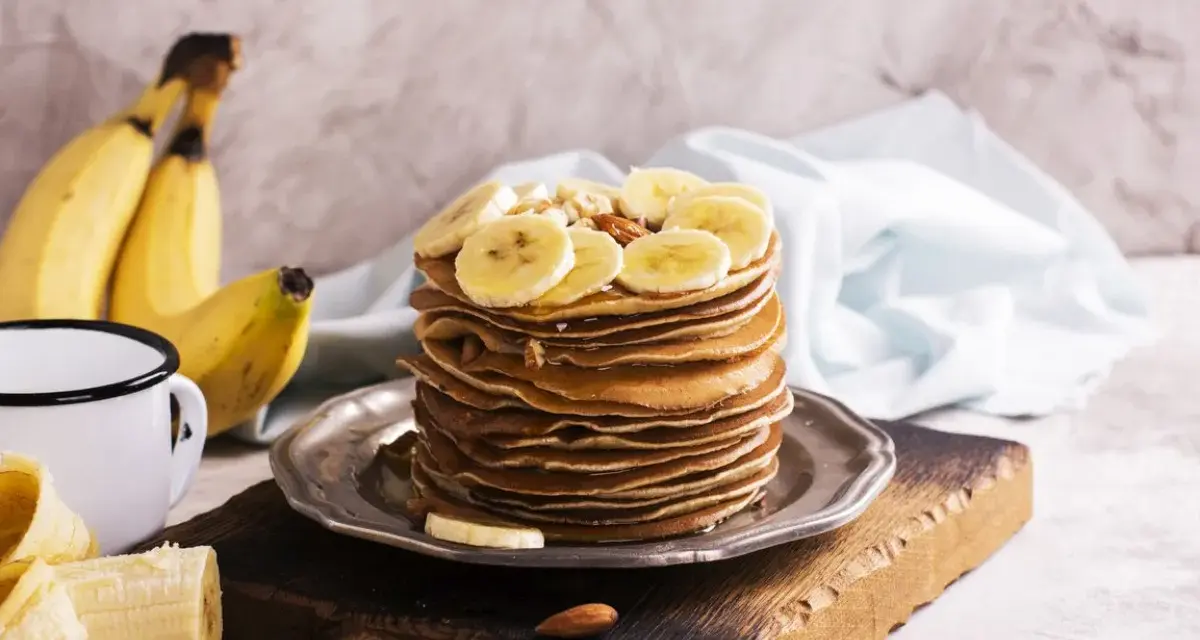 Stos naleśników z plasterkami banana i orzechami. Idealny pomysł, co zrobić z bananów na pyszne śniadanie.
