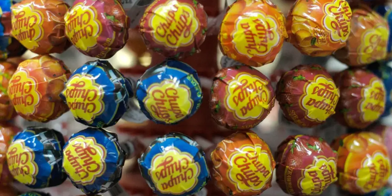 Zbliżenie na kolorowe lizaki Chupa Chups w opakowaniach z owocowymi wzorami.