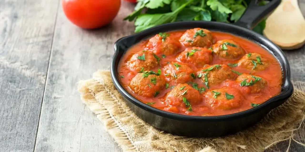 Pyszne pulpeciki w sosie pomidorowym, posypane natką pietruszki, gotowe do podania.