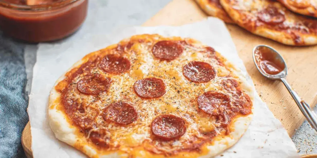 Pyszna pizza z tortilli na patelni, z serem i pepperoni, gotowa do podania. Obok sos i łyżeczka.