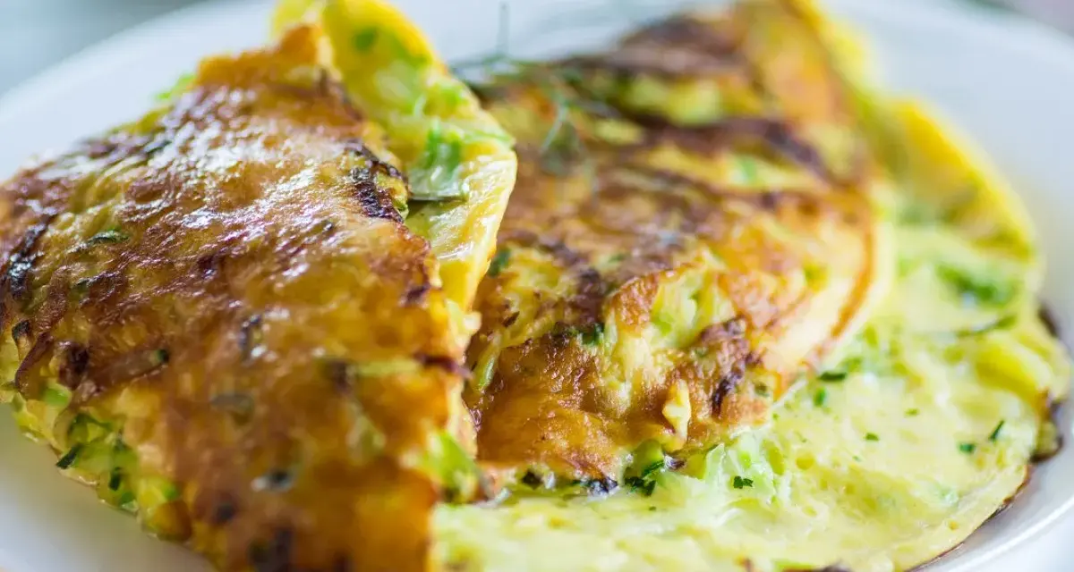 Złocisty omlet z cukinią, delikatnie zrumieniony, podany na białym talerzu.