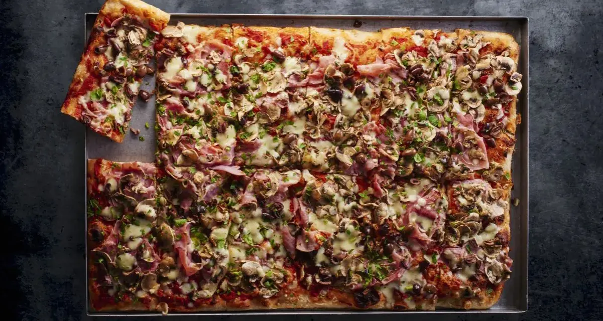 Najlepsza pizza domowa na dużą blachę, obficie posypana pieczarkami, szynką i oliwkami. Idealna na rodzinne spotkanie.