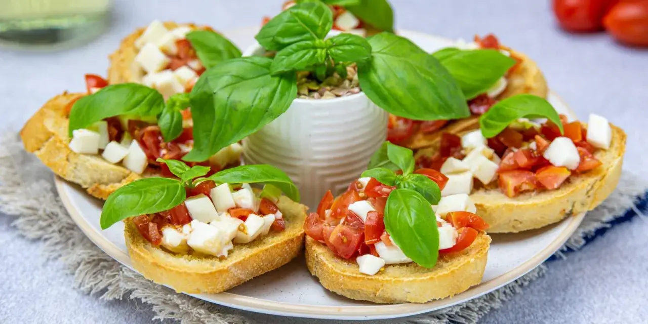 Bruschetta z pomidorami i mozzarellą, świeża bazylia i chrupiące pieczywo. Idealny przepis na letnią przekąskę.