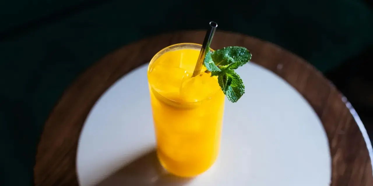 Orzeźwiający koktajl z mango, z lodem i listkami mięty, podany w szklance ze słomką.
