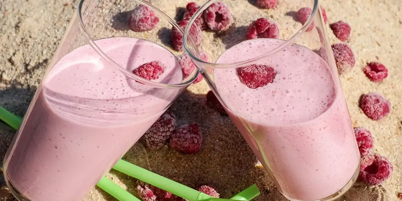 Dwa pyszne malinowe smoothie na piasku, idealne na lato. Inspiracja na zdrowe smoothie przepisy.