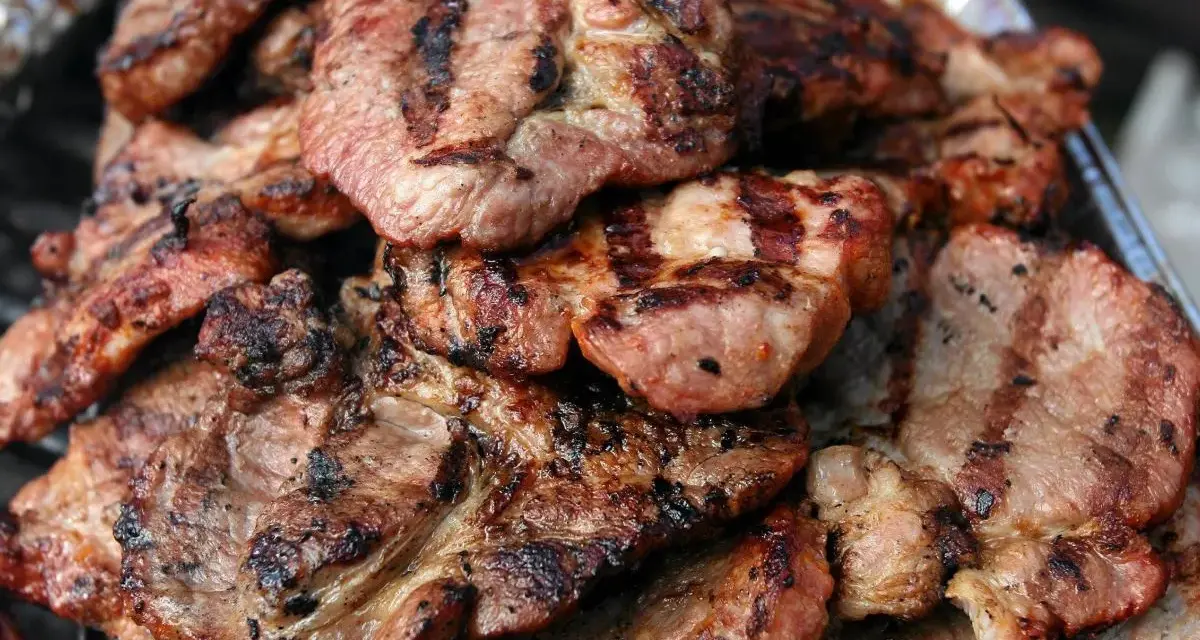 Soczysta karkówka z grilla, idealna po marynacie. Grillowane plastry mięsa z charakterystycznymi paskami.