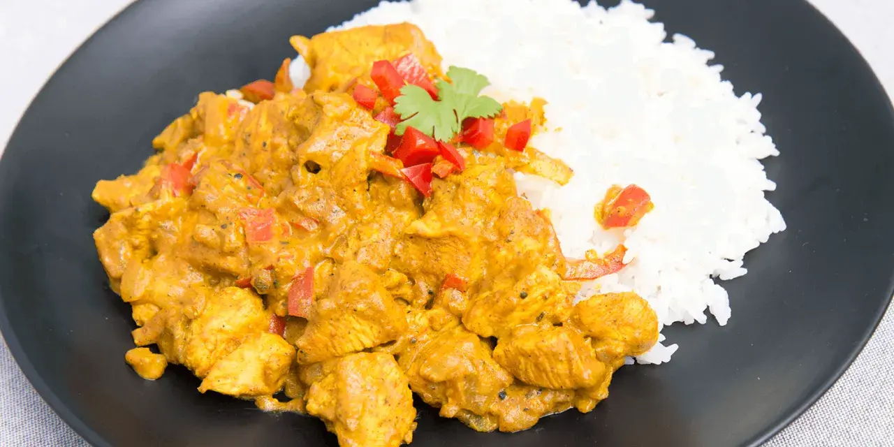 Kurczak w sosie curry z ryżem, posypany papryką i kolendrą. Prosty przepis na pyszny obiad.