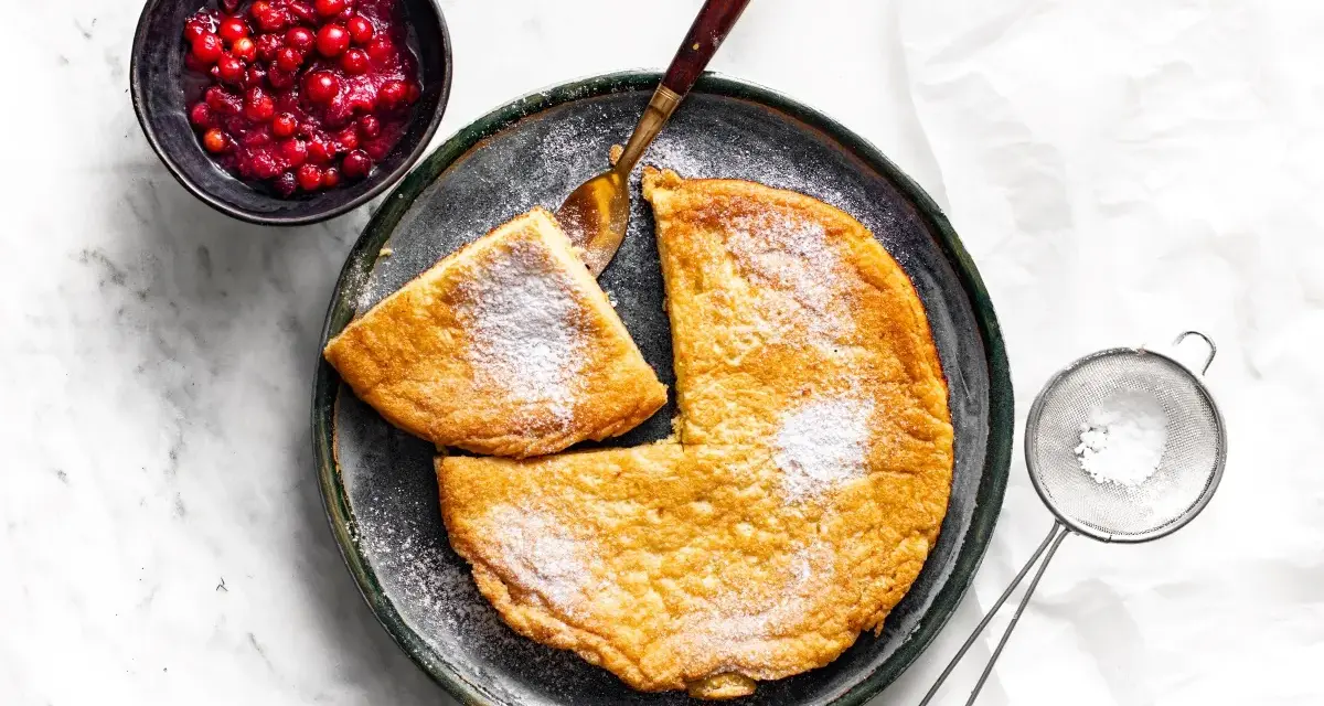 Puszysty omlet z air fryera, posypany cukrem pudrem, podany z żurawiną. Idealny na śniadanie.