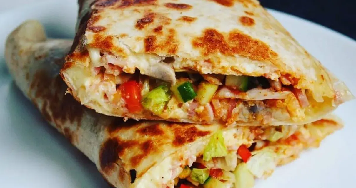 Złocista tortilla z jajkiem, serem i szynką, wypełniona warzywami, usmażona na patelni. Pyszne danie na szybki posiłek.