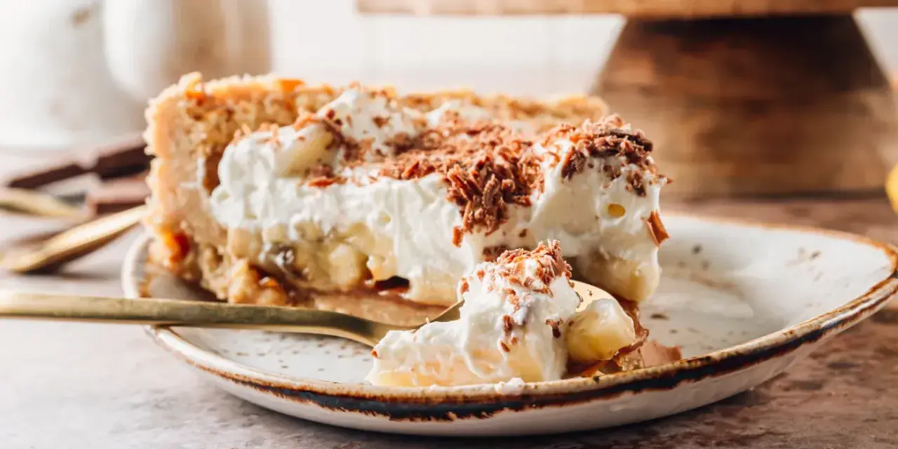 Pyszne ciasto migdałowiec z bananami i bitą śmietaną, posypane czekoladą. Idealne na deser!