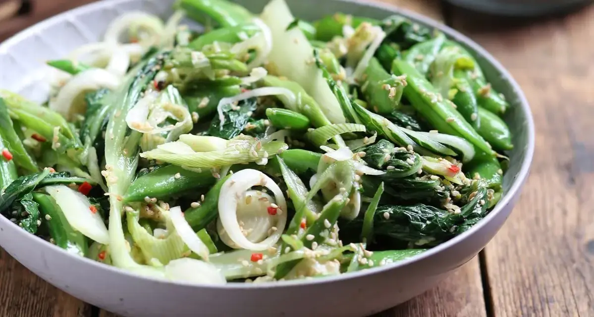 Sałatka z pak choi, groszku cukrowego i cebuli dymki, posypana sezamem. Idealna do dań kuchni azjatyckiej, świetne przepisy na kapustę pak choi.